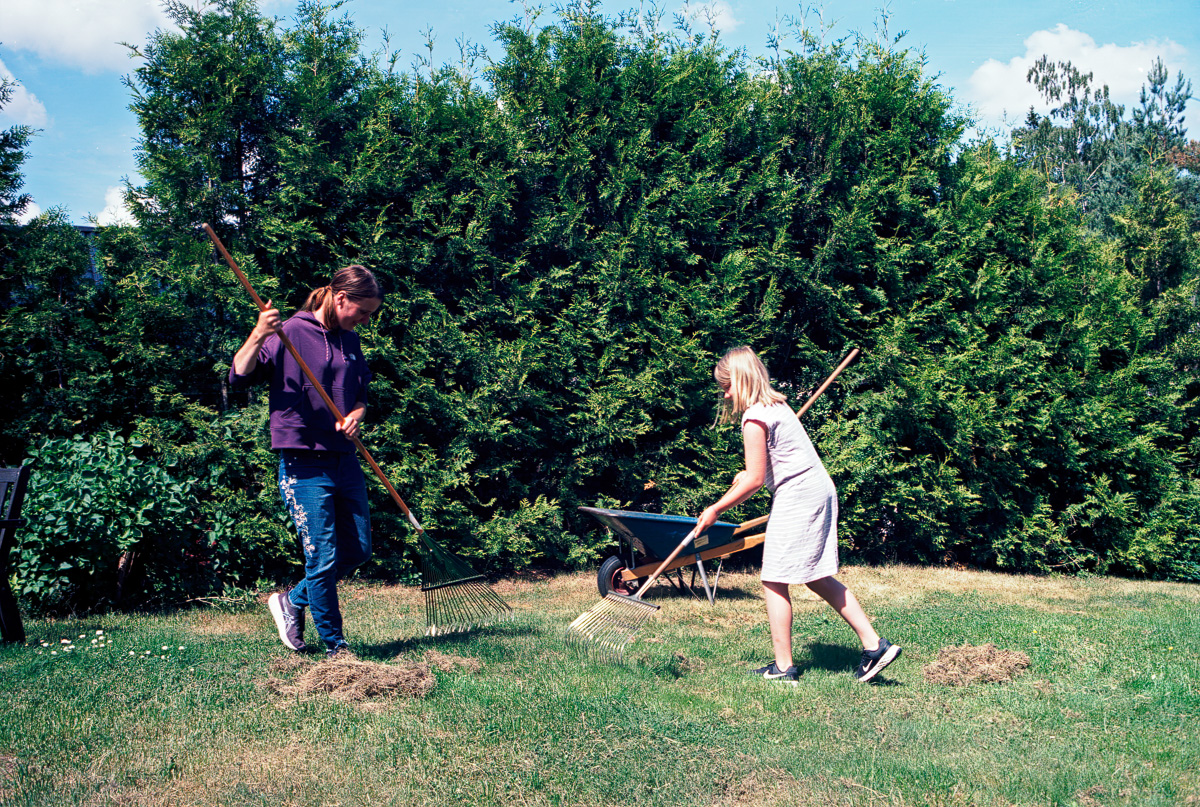 Karin och Saga räfsar gräs